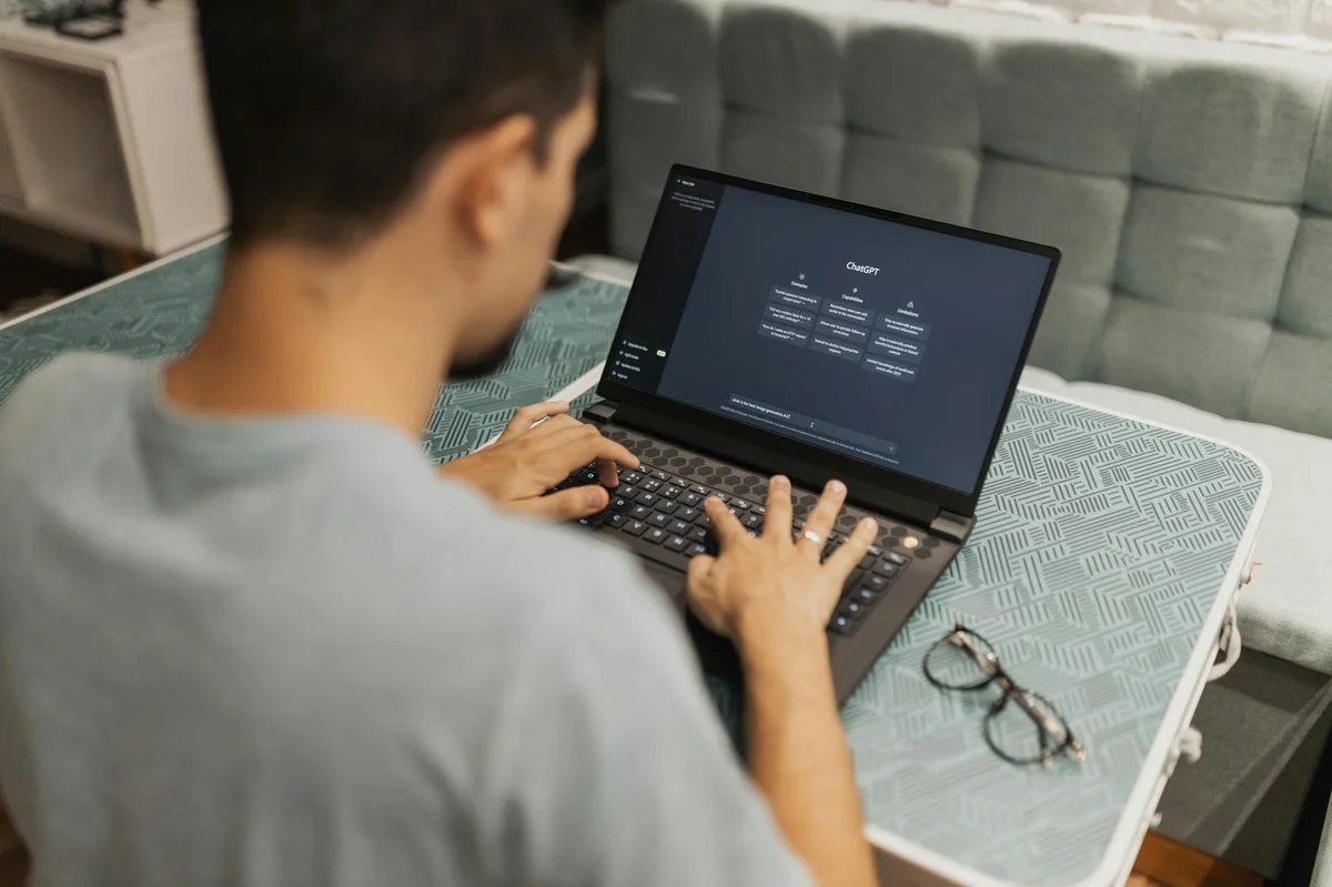 Plugins de IA: cómo instalar capacidades completas sin acumu... — A man working on a laptop displaying ChatGPT's interface in an indoor setting.