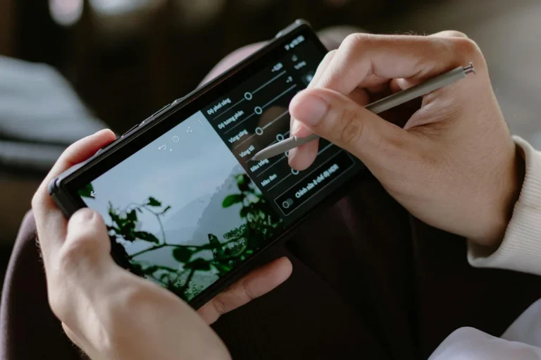 Constancia en TikTok sin quemarte: la guía del libro para un... — Close-up of a person editing photos on a smartphone with a stylus indoors.
