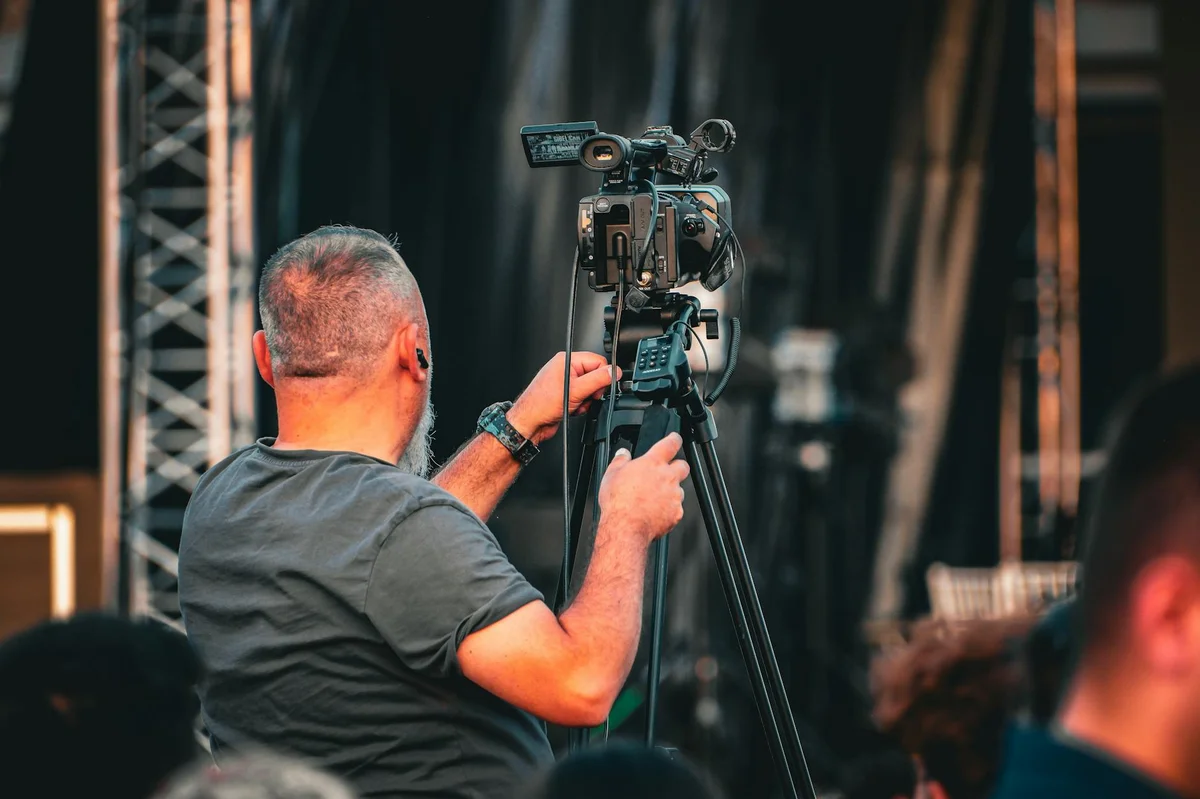 TikTok 2026: la guía definitiva que todo creador necesita le... — A professional cameraman operating a video camera on a tripod during an outdoor