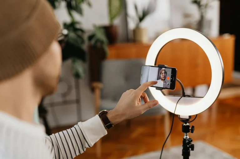Comunidad en TikTok: lo que el libro enseña sobre convertir... — Adult male creating video content with smartphone and ring light in a cozy indoo