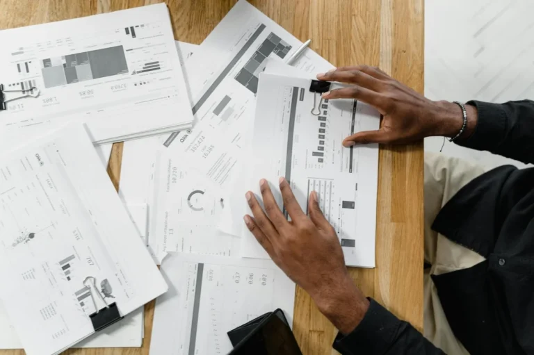 El arte de preguntar con IA: cinco niveles para descomponer... — Top view of a professional reviewing financial documents at a wooden workspace.
