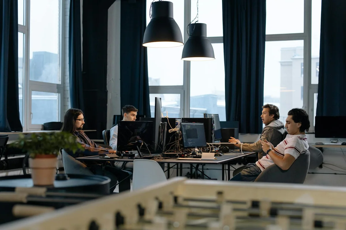 Pensamiento extendido y Opus: cuándo merece la pena pagar po... — Workers collaborate in a modern office with computers, showcasing teamwork in te