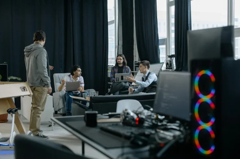 Proyectos largos con IA: el pase de testigo que mantiene la... — A group of professionals engaged in a casual meeting at a modern office, discuss