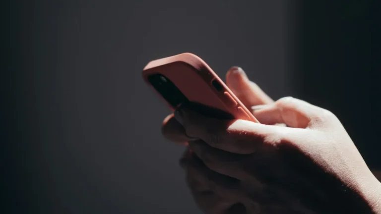 El algoritmo de TikTok en 2026: lo que el libro revela y nad... — Close-up of hands holding a smartphone in dim lighting, showcasing texting or br