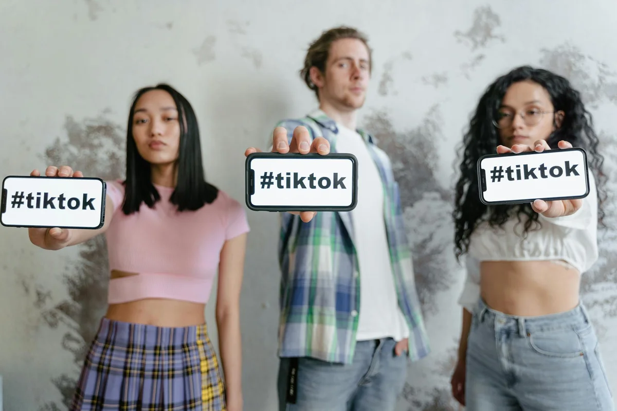 SEO en TikTok 2026: lo que el libro enseña sobre visibilidad... — Group of young adults holding phones with #tiktok indoors, showcasing social med