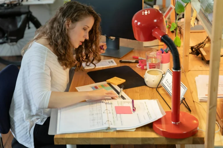 Como dejar de estar ocupado y empezar a ser eficaz: lo que e... — Woman working intently at her desk in a cozy office, surrounded by documents and