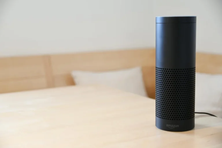 Tu negocio como repositorio consultable: cómo organizar arch... — A black smart speaker resting on a light-colored wooden table in a cozy indoor s