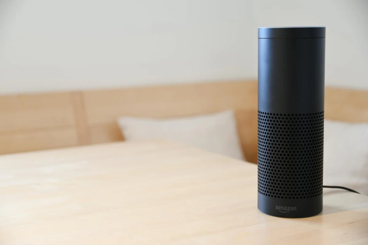 Tu negocio como repositorio consultable: cómo organizar arch... — A black smart speaker resting on a light-colored wooden table in a cozy indoor s