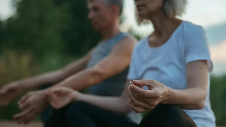 Senior couple practicing meditation outdoors, focusing on mindfulness and tranquility.