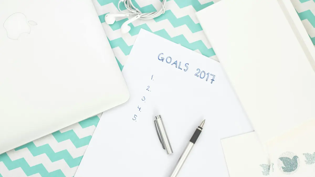 Photo of a workspace featuring a notepad labeled Goals 2017, pen, and laptop for planning.
