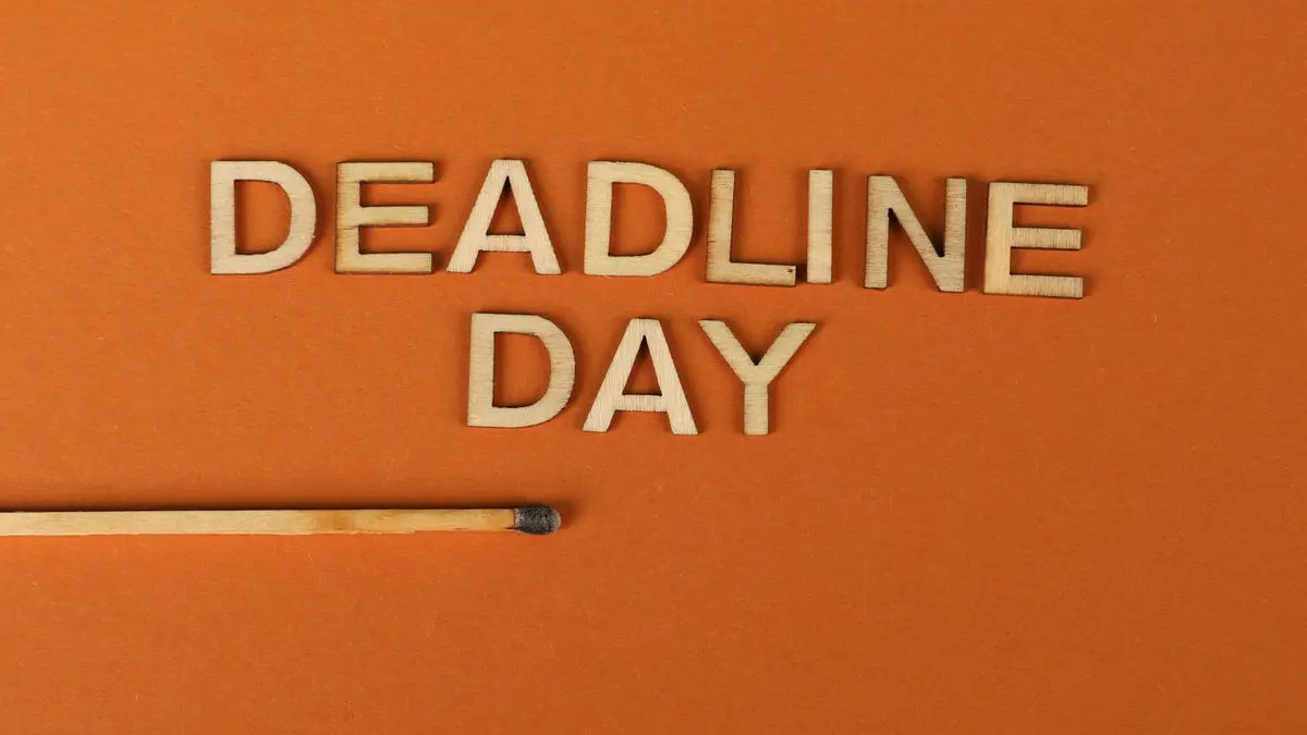 Conceptual image of a deadline with wooden letters and burnt matchstick on orange background.
