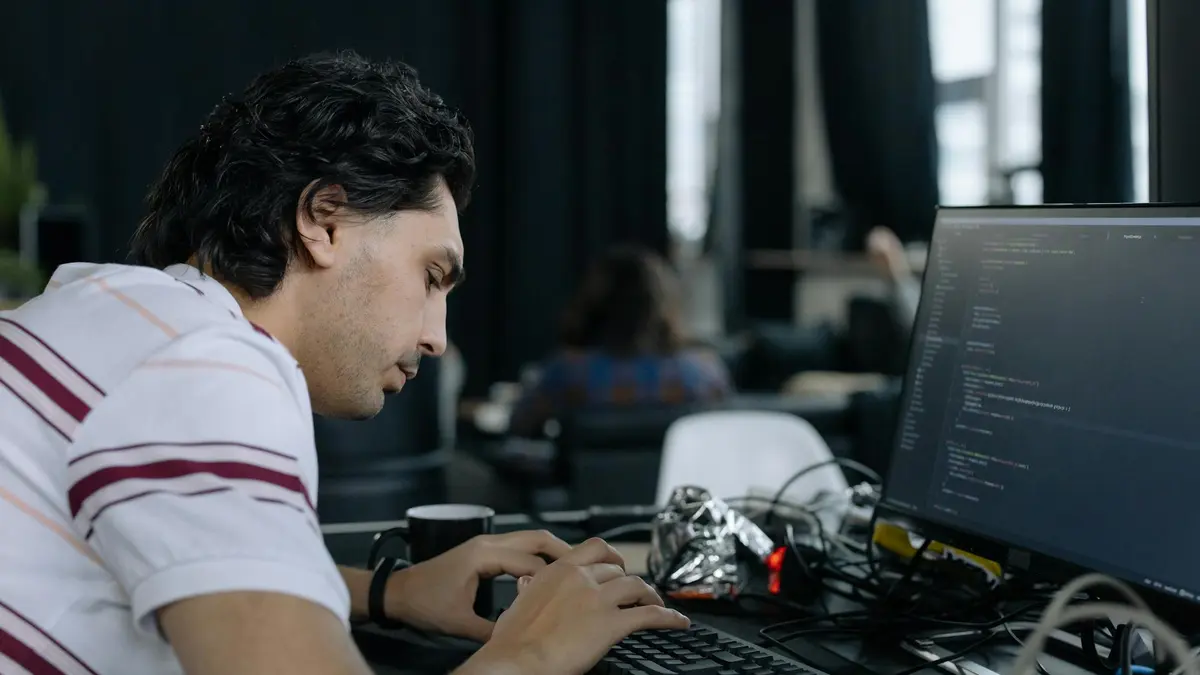 A coder intensely typing at a workstation in a contemporary office setup.